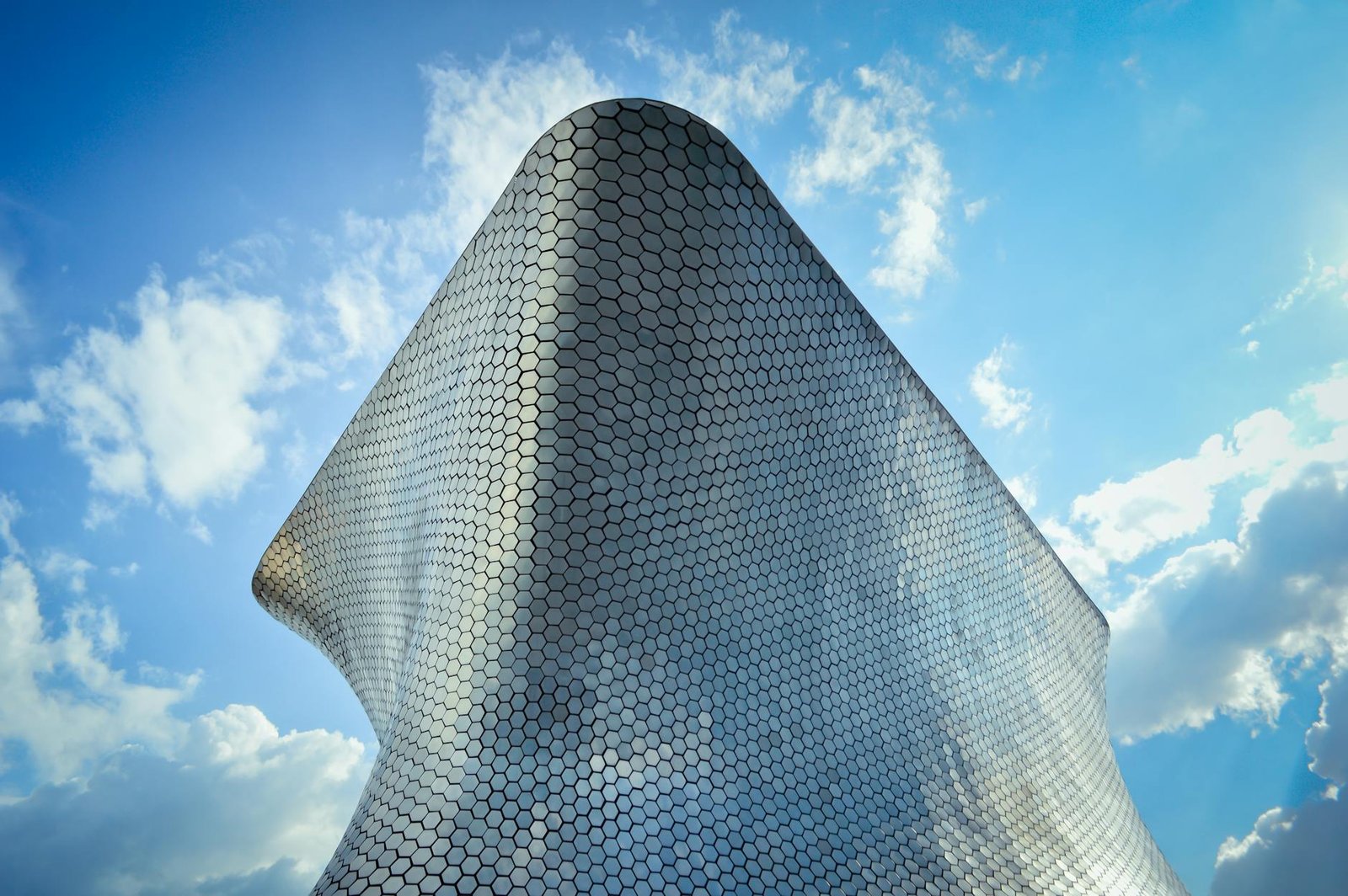 Low angle view of the modern and futuristic Soumaya Museum against a bright sky in Mexico City.