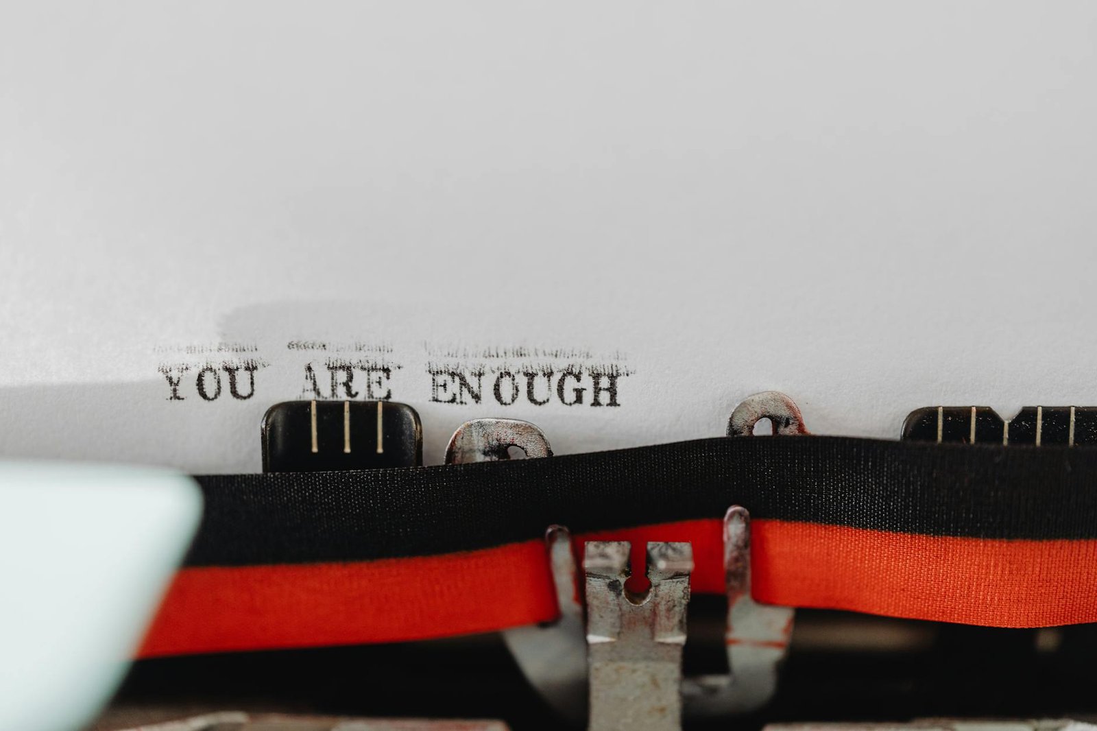 Close-up of a typewriter with the message 'YOU ARE ENOUGH' typed on paper.