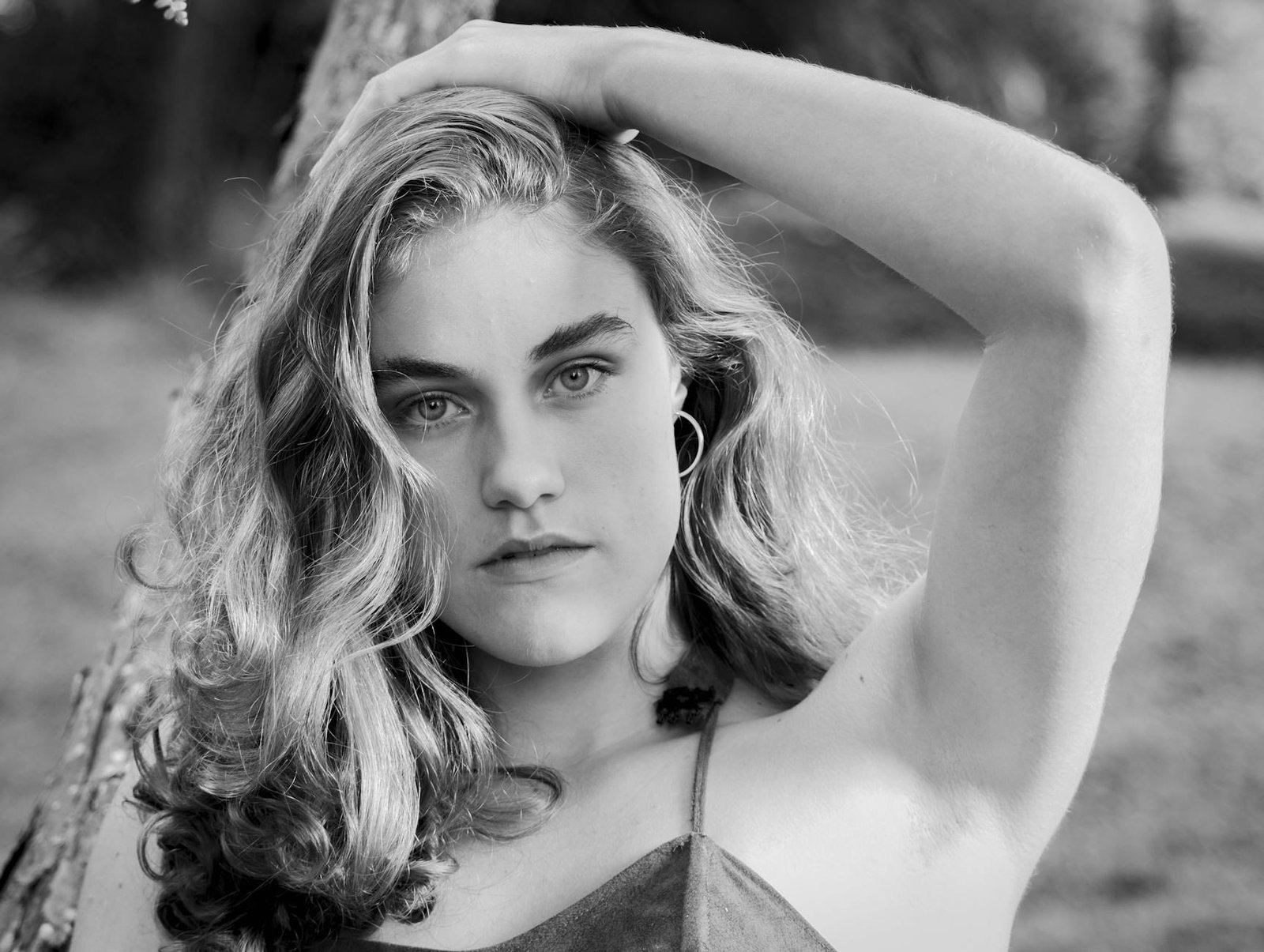 Elegant black and white portrait of a young woman in a natural setting.