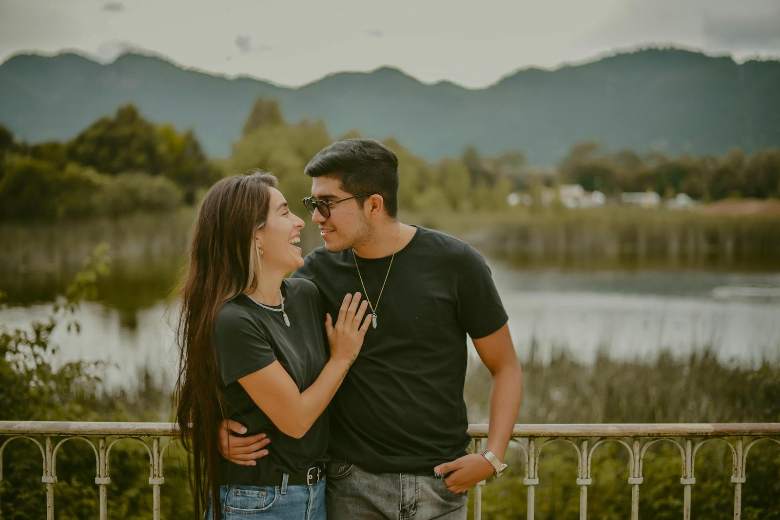 A joyful couple embracing and laughing by a picturesque lake in Mexico.