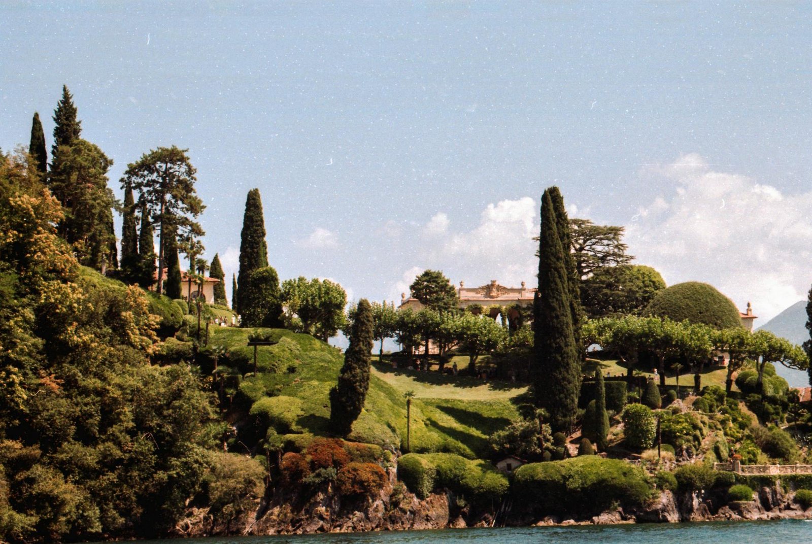 Scenic view of Villa del Balbianello surrounded by lush greenery in Lake Como, Italy.