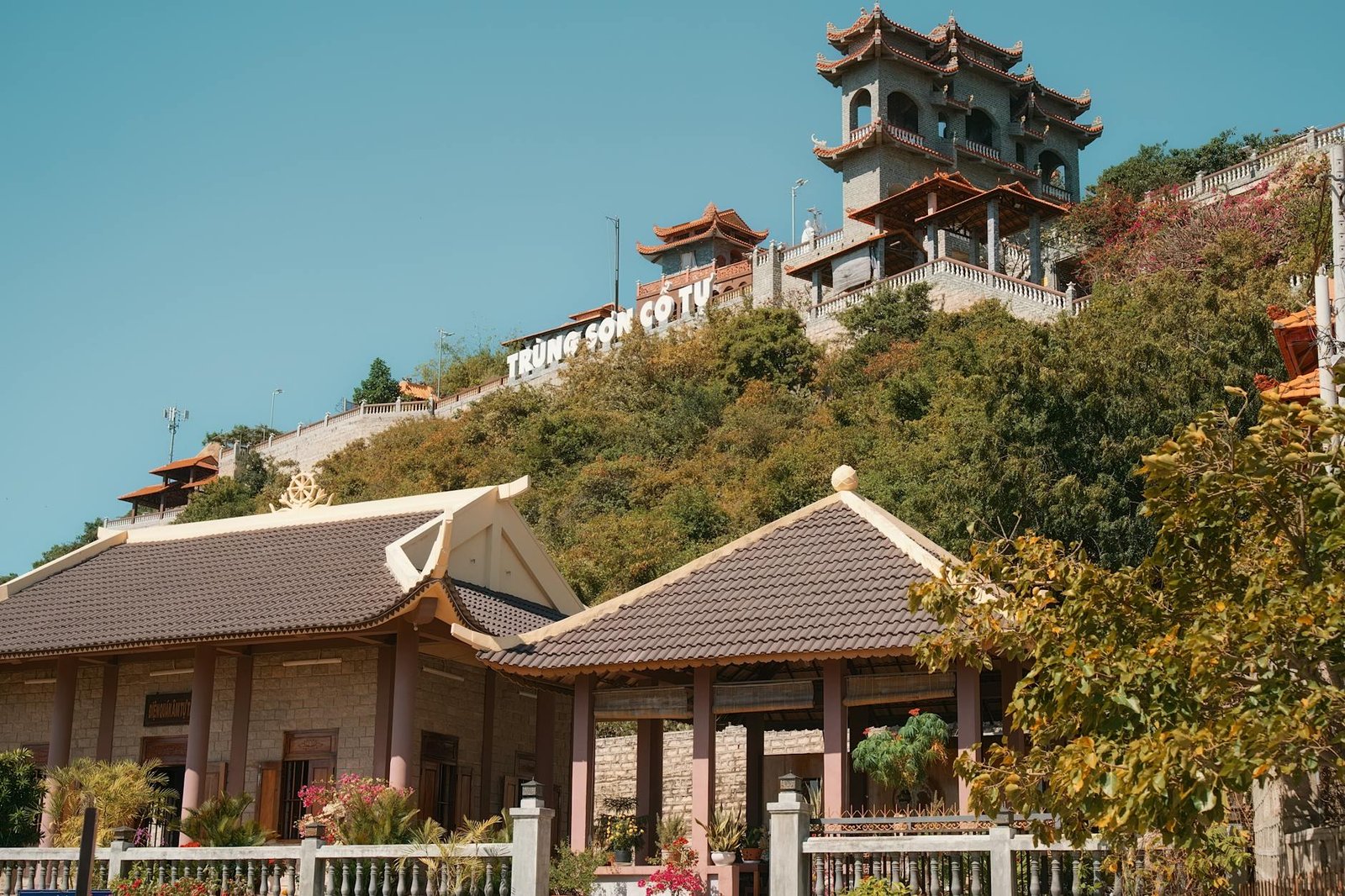 Trung Son Co Tu Pagoda on a sunny hillside, showcasing traditional architecture and vibrant natural surroundings.