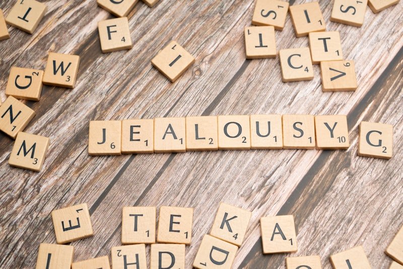 scrabble tiles spelling the word jellousy on a wooden surface