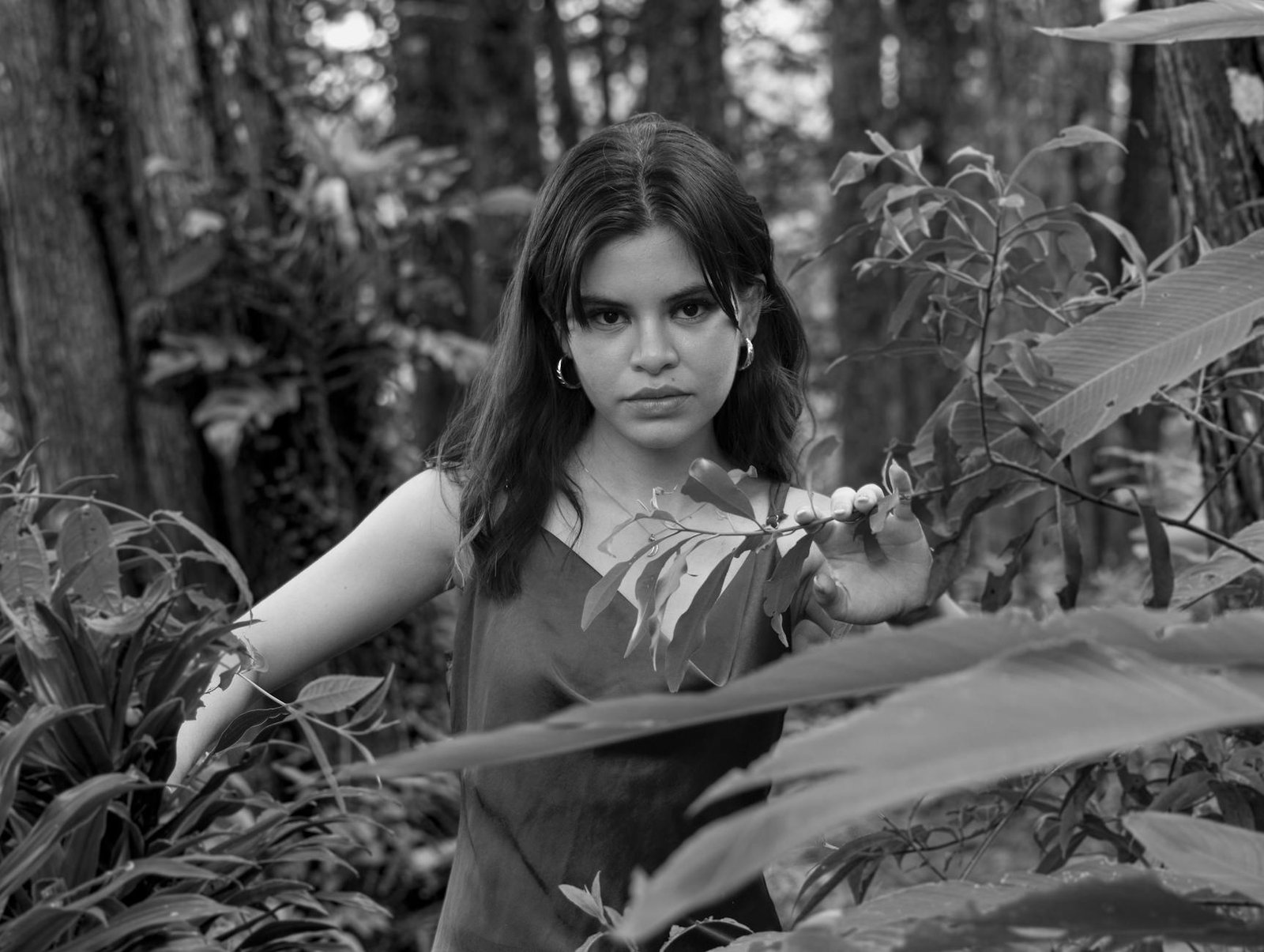 A woman poses thoughtfully in a lush Costa Rican forest, captured in black and white.