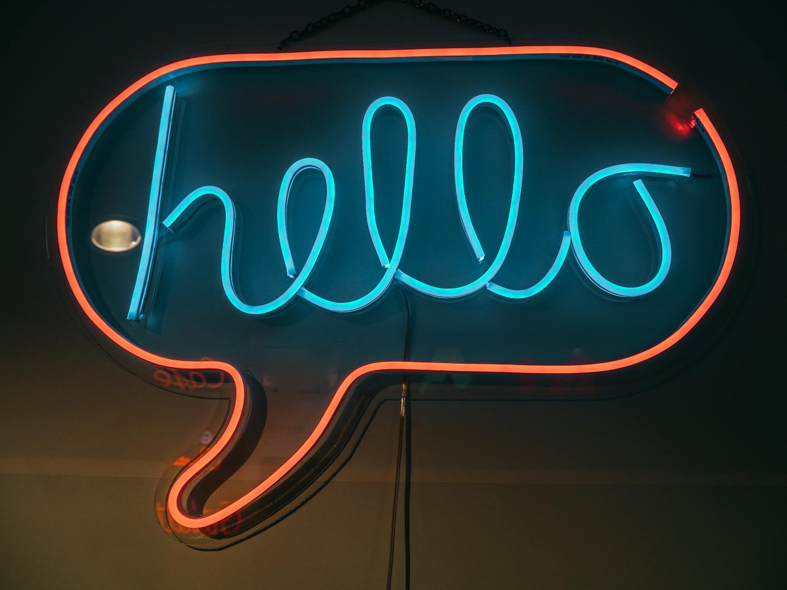 Vibrant neon sign displaying the word 'hello' in a speech bubble with blue and red illumination.