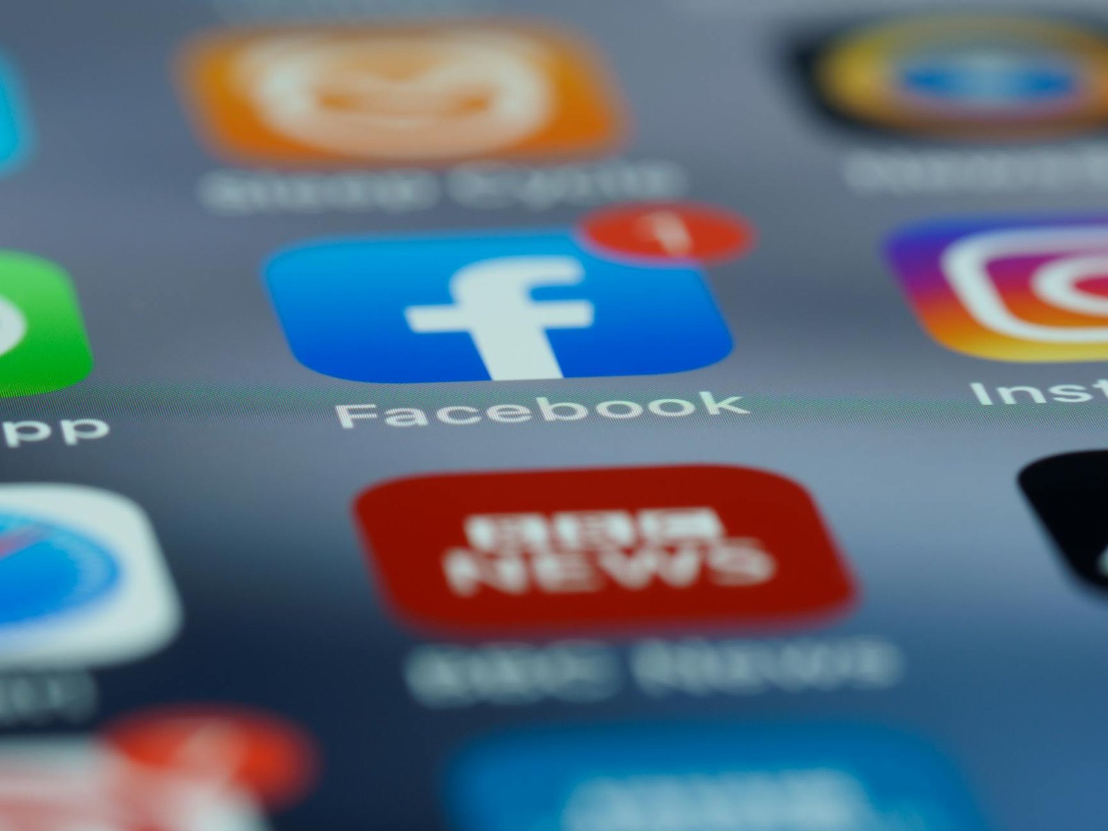 Close-up of smartphone screen displaying various social media app icons including Facebook.