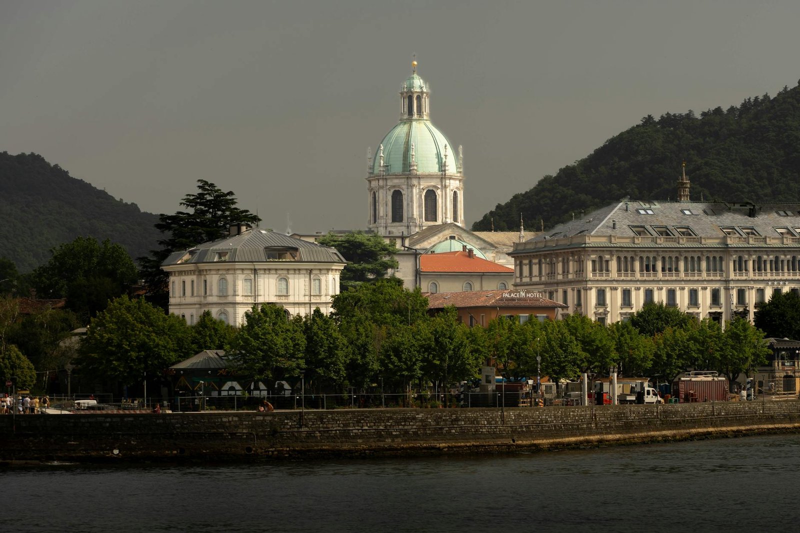 A picturesque view of Como Cathedral surrounded by historic buildings and lush greenery by Lake Como.