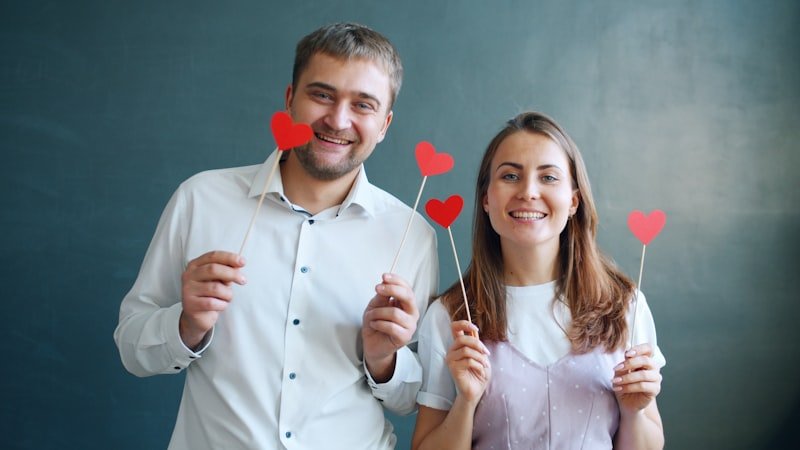 Couple holding red heart decorations