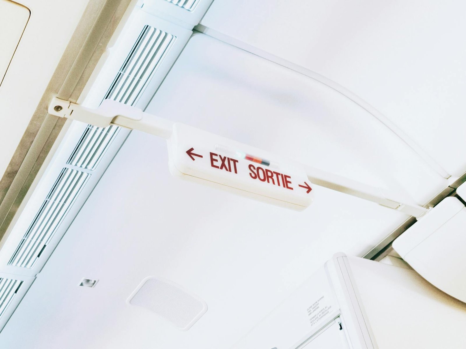 Close-up of airplane interior with exit sign, showing bilingual text EXIT/SORTIE.