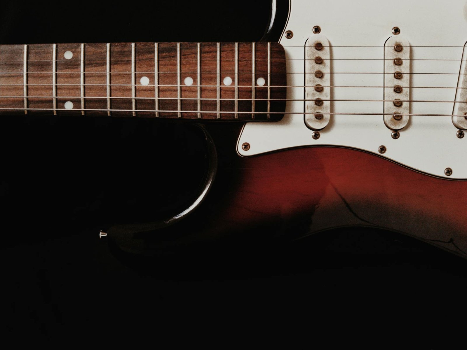 Detailed shot of an electric guitar with a dark background emphasizing the instrument's features.