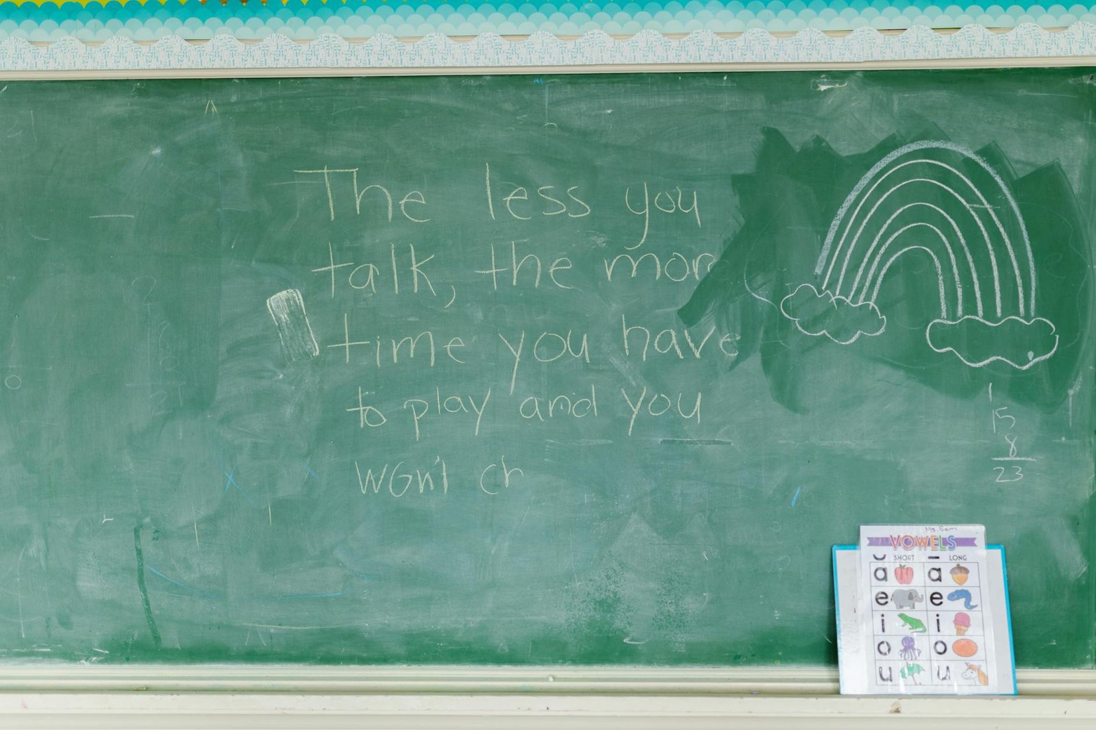 A classroom chalkboard with a motivational message and rainbow drawing, enhancing a learning environment.