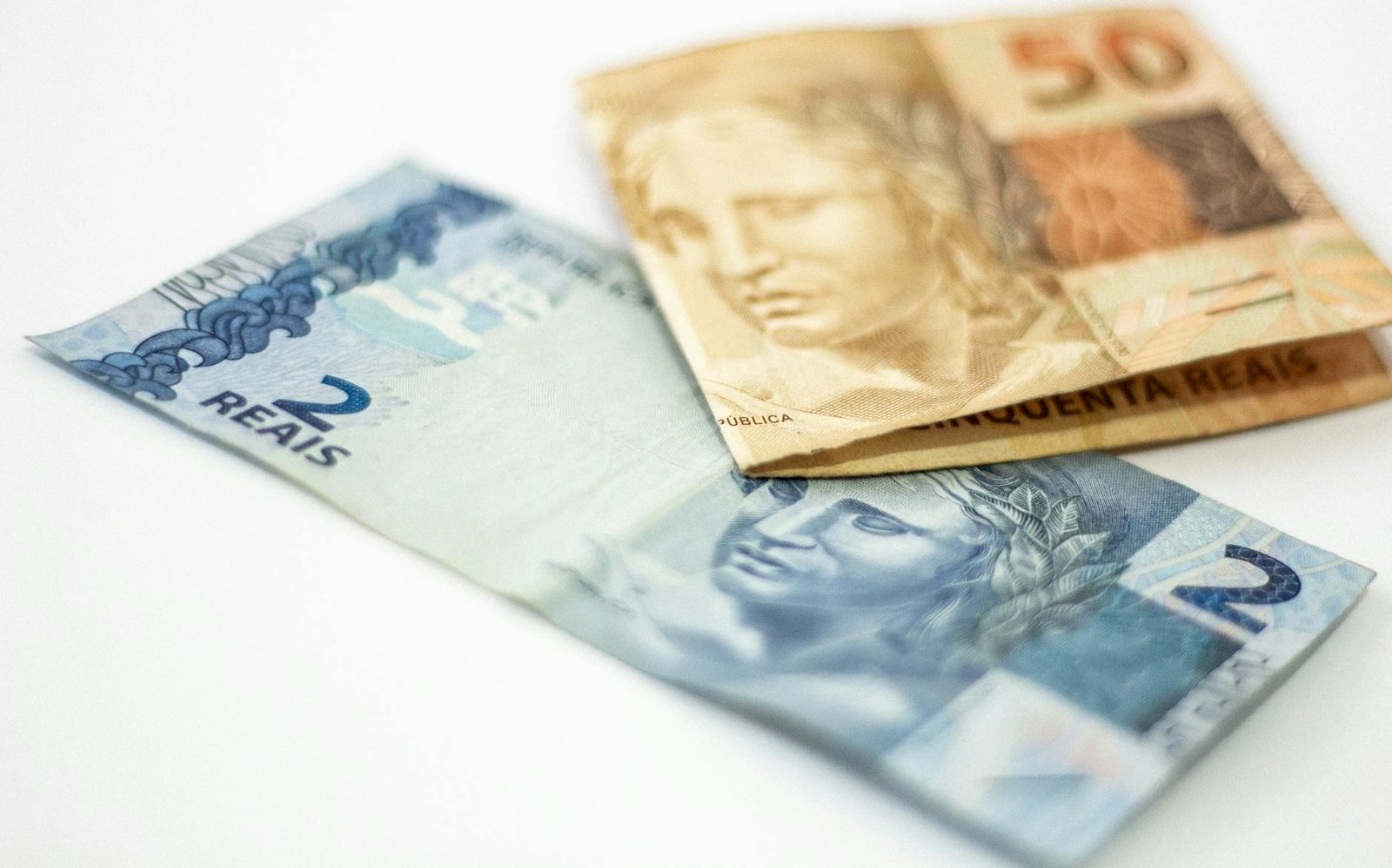 Close-up view of Brazilian banknotes, 2 and 50 reals, on a white background.