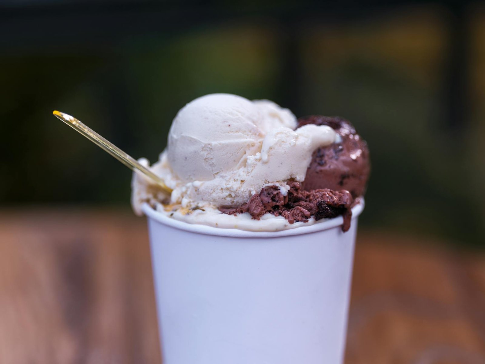 Close-up of vanilla and chocolate ice cream in a white cup with a spoon. Perfect summer dessert.