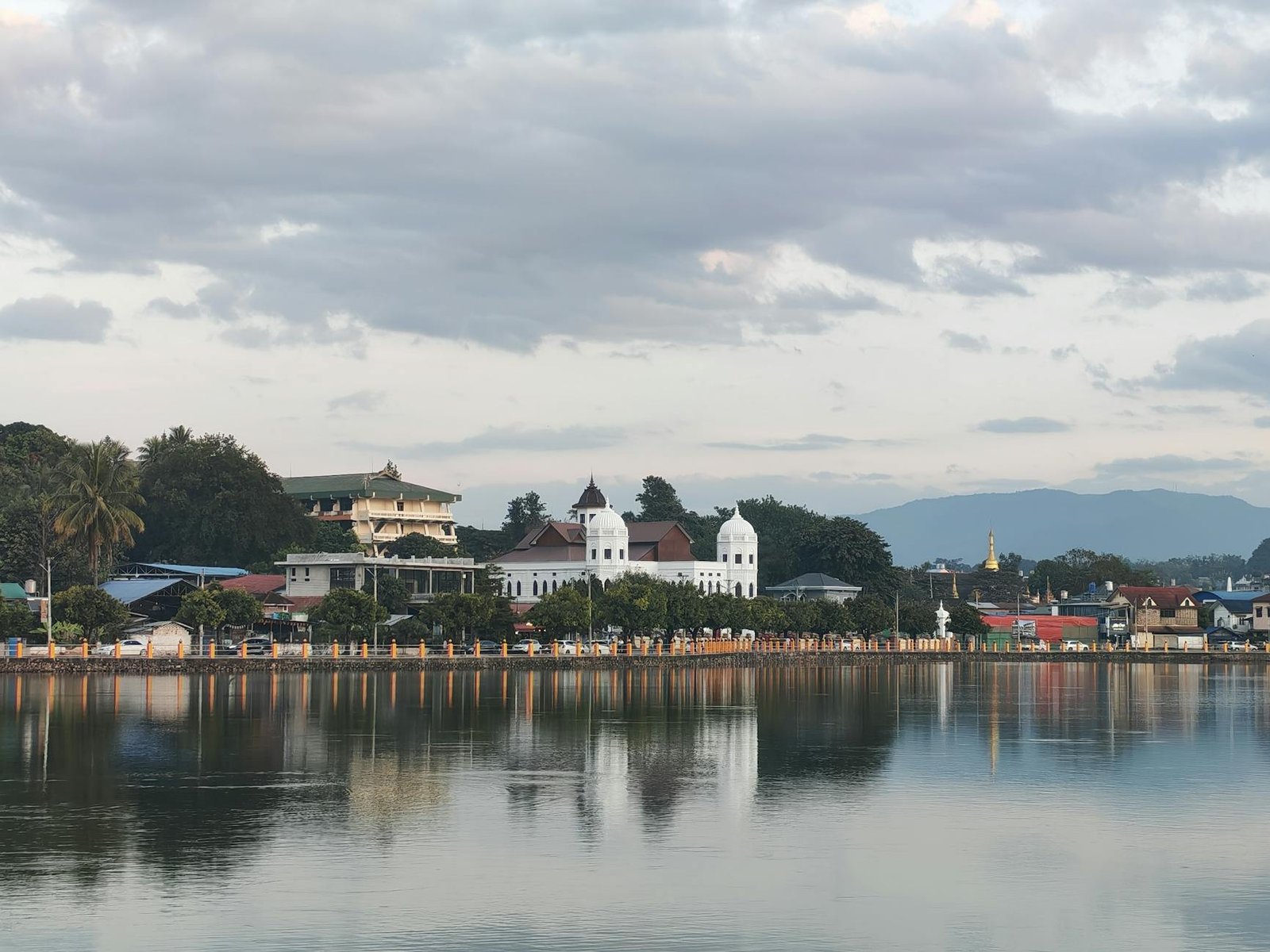 Beautiful reflection of Keng Tung's heritage buildings on a serene lake with picturesque clouds.