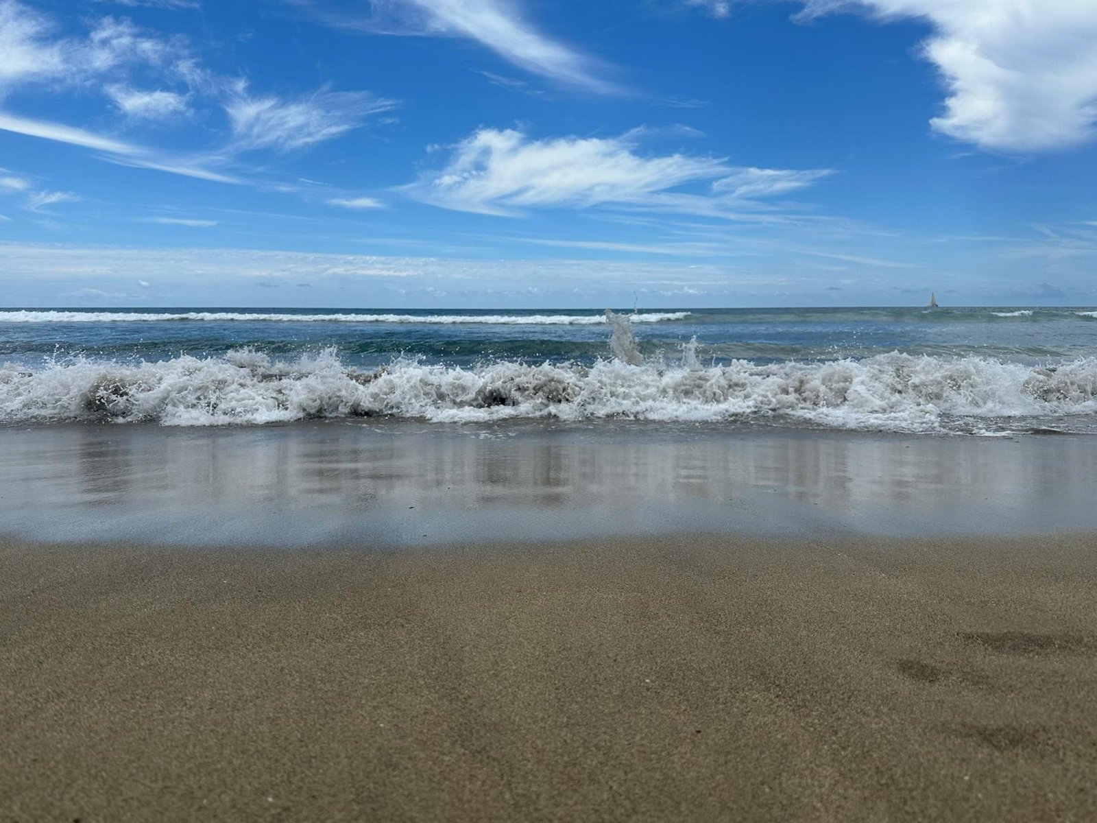Idyllic sandy beach with gentle waves and vibrant blue sky. Perfect for relaxation and travel inspiration.