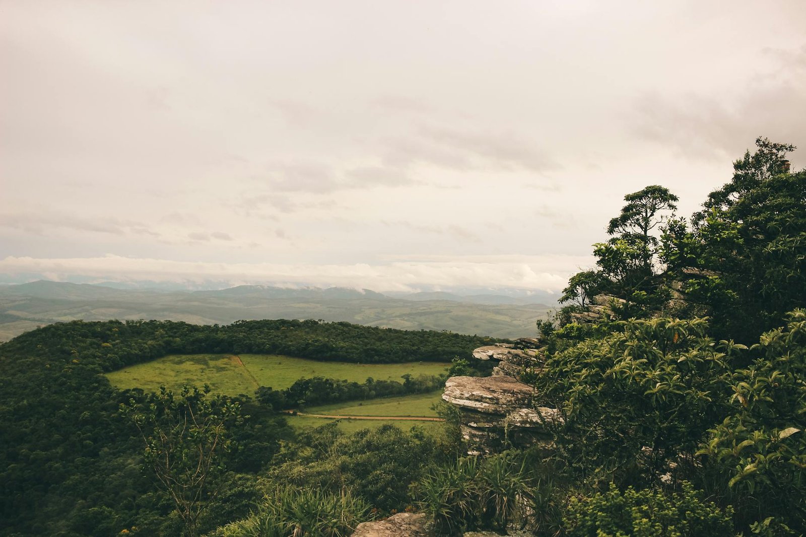 Explore the lush greenery and rocky terrain of São Tomé das Letras, Brazil, under a muted sky.