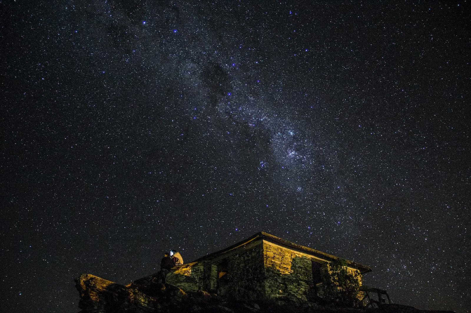A captivating view of the Milky Way over a stone house in São Tomé das Letras, Brazil.