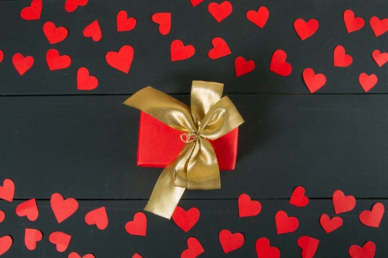 a red gift box with a gold ribbon and a bow