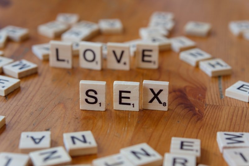 A wooden table topped with scrabble letters spelling love and sex