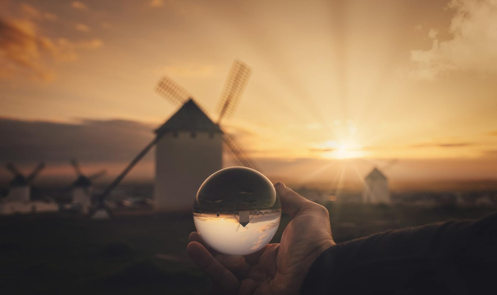 Sunset view of historic windmills through a crystal ball in Campo de Criptana, Spain.