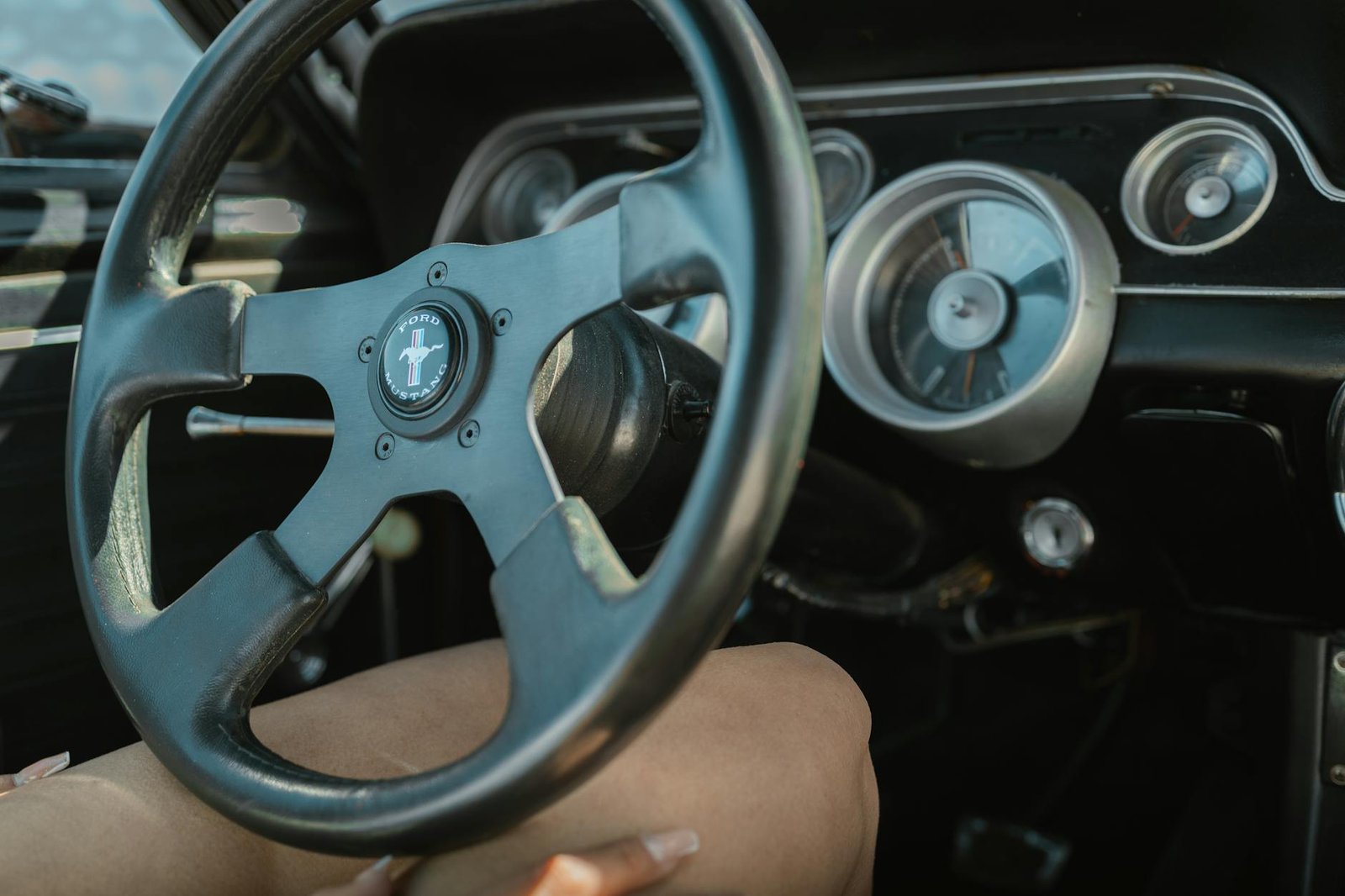 Close-up of a vintage Ford Mustang steering wheel and dashboard showcasing retro car design.
