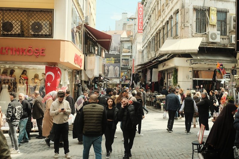 a crowd of people walking down a street next to tall buildings
