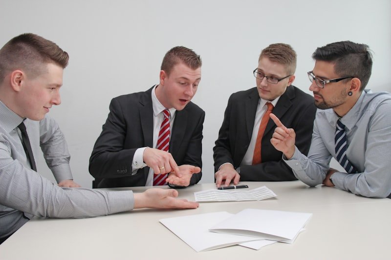 four men sitting at desk talking