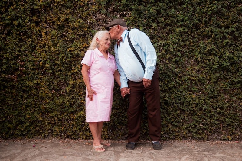 A man and a woman standing in front of a hedge